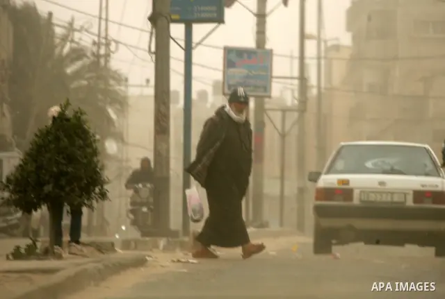 Palestinians walk at a street during cold winds and sand storms in the southern Gaza Strip town of Rafah on February 7, 2012. Photo by Abed Rahim Khatib