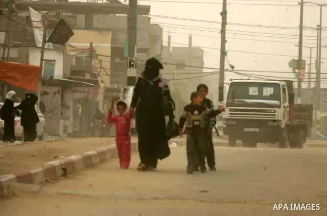Palestinians walk at a street during cold winds and sand storms in the southern Gaza Strip town of Rafah on February 7, 2012. Photo by Abed Rahim Khatib