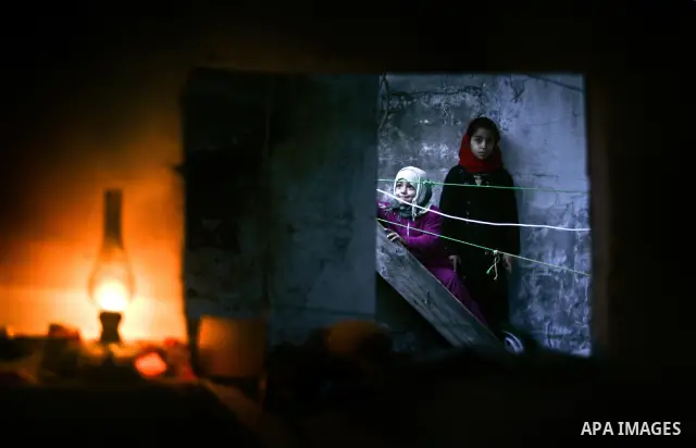 Palestinian girls are seen through a window of their familiy's home during an electricity power cut in the Jabaliya refugee camp, Gaza Strip, 07 February 2012. Electricity is reported to be cut for 12 hours every day as...