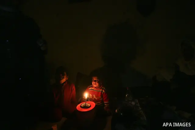 Two Palestinian children playing games on the device at their familiy's home during an electricity power cut in the Jabaliya refugee camp, Gaza Strip, 07 February 2012. Electricity is reported to be cut for 12 hours ever...