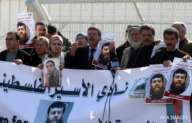 Palestinian protesters hold a placard that reads in Arabic "Khodr Adan our dignity is also more precious than food" during a demonstration outside the Israeli Ofer military prison, near the West Bank town of Betunia, on...