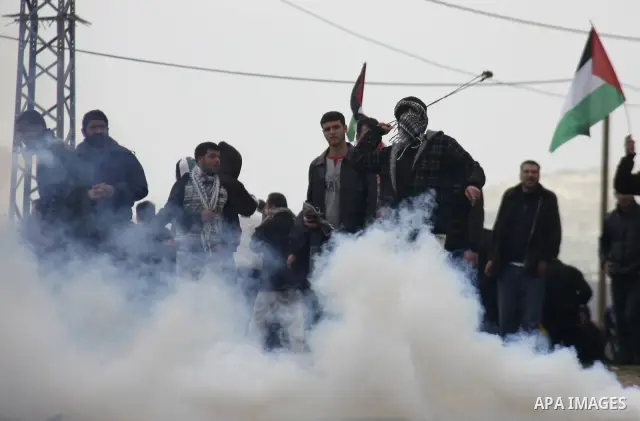 Palestinians protester runs through a cloud of teargas fired by Israeli soldiers during a demonstration against the expropriation of Palestinian land by Israel in the village of Kfar Qaddum, near the West Bank city of Na...
