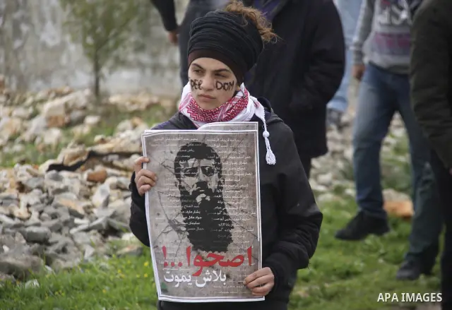 Palestinian protesters hold a placard that reads in Arabic ''Khodr Adan our dignity is also more precious than food'' during a demonstration outside the Israeli Ofer military prison, in the village of Kufr Qaddum against...