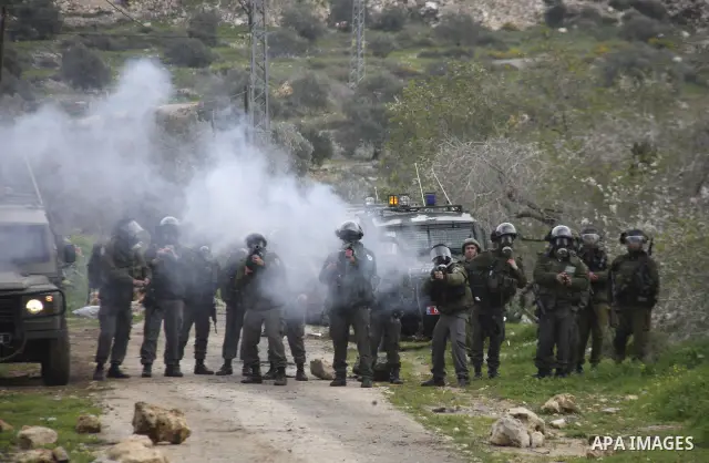 Palestinians protester runs through a cloud of teargas fired by Israeli soldiers during a demonstration against the expropriation of Palestinian land by Israel in the village of Kfar Qaddum, near the West Bank city of Na...