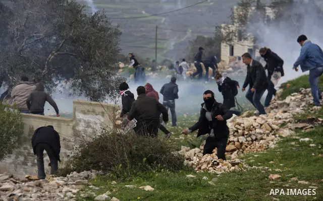 Palestinians protester runs through a cloud of teargas fired by Israeli soldiers during a demonstration against the expropriation of Palestinian land by Israel in the village of Kfar Qaddum, near the West Bank city of Na...