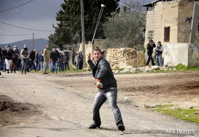 A Palestinian youth hurls a stone at Israeli troops, during a protest in the village of Kufr Qaddum against the expansion of the nearby Jewish settlement of Kdumim, in the northern West Bank, Friday, Feb.10, 2012. Photo...