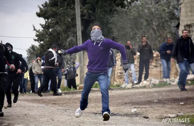 A Palestinian youth hurls a stone at Israeli troops, during a protest in the village of Kufr Qaddum against the expansion of the nearby Jewish settlement of Kdumim, in the northern West Bank, Friday, Feb.10, 2012. Photo...