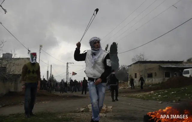 A Palestinian youth hurls a stone at Israeli troops, during a protest in the village of Kufr Qaddum against the expansion of the nearby Jewish settlement of Kdumim, in the northern West Bank, Friday, Feb.10, 2012. Photo...