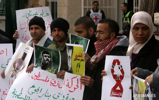 Palestinian protesters shout slogans during a demonstration in support of Khader Adnan (portrait), a Palestinian held in an Israeli prison without trial and who is on hunger strike since December 18, outside the Red Cros...