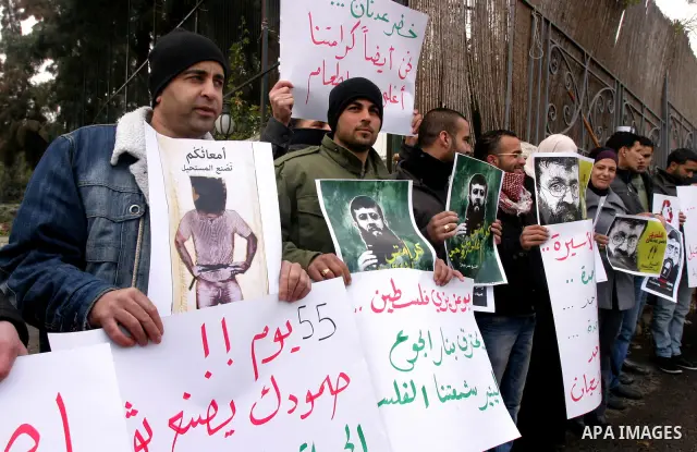 Palestinian protesters shout slogans during a demonstration in support of Khader Adnan (portrait), a Palestinian held in an Israeli prison without trial and who is on hunger strike since December 18, outside the Red Cros...