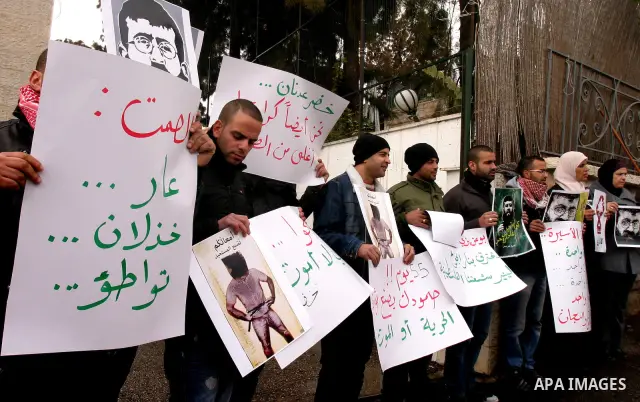 Palestinian protesters shout slogans during a demonstration in support of Khader Adnan (portrait), a Palestinian held in an Israeli prison without trial and who is on hunger strike since December 18, outside the Red Cros...