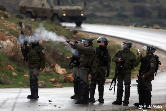 Israeli border police officers fire tear gas towards Palestinian demonstrators, during a protest in the West Bank village of Nabi Saleh near Ramallah, Friday, Feb. 10, 2012. Photo by Issam Rimawi