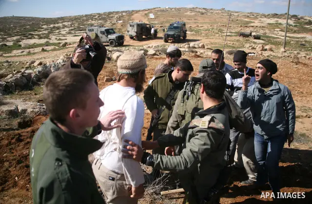 A Jewish settler from the Susia Israeli settlement argues with Israeli soldiers after a donkey was used by Palestinian farmers to transport trees to be planted on their land close to Susia village, in the Israeli occupie...