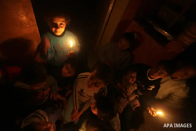 Palestinian children sit at their home during a power cut at the Shati refugee camp in Gaza City on February 11, 2012. The Gaza energy authority announced that if fuel doesn't enter the coastal enclave, the Gaza Strip wi...
