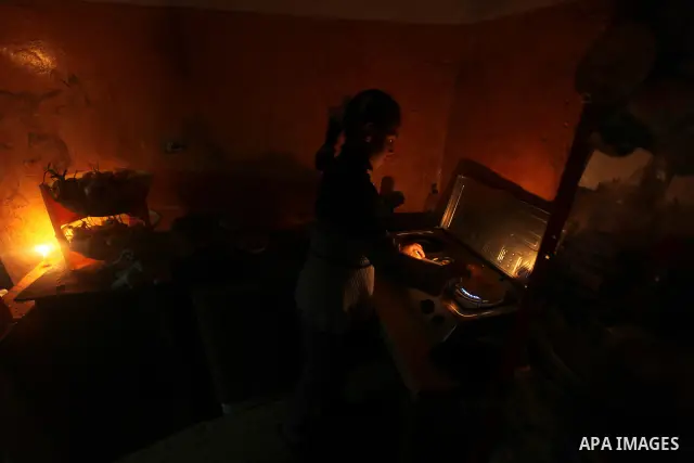 Palestinian children sit at their home during a power cut at the Shati refugee camp in Gaza City on February 11, 2012. The Gaza energy authority announced that if fuel doesn't enter the coastal enclave, the Gaza Strip wi...