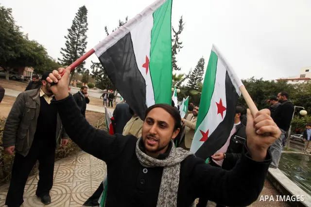 Palestinian demonstrators hold the Syrian national flag during a rally against Syrian President Bashar al-Assad's regime on February 12, 2012 in Gaza City. Photo by Majdi Fathi