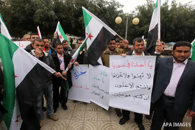 Palestinian demonstrators hold the Syrian national flag during a rally against Syrian President Bashar al-Assad's regime on February 12, 2012 in Gaza City. Photo by Majdi Fathi