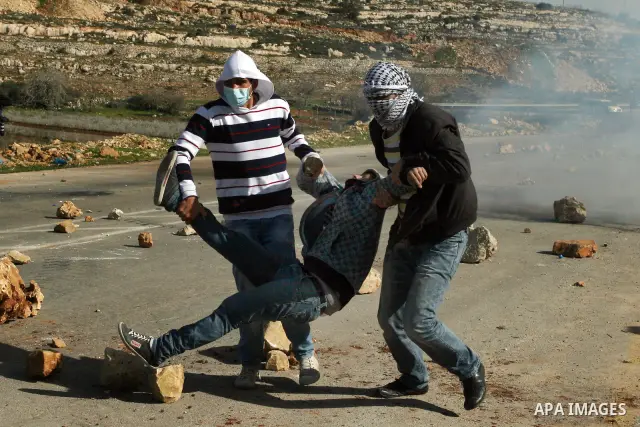 Palestinian protesters run to an injured youth during clashes with Israel security forces outside the Ofer military prison near the West Bank city of Ramallah, Monday, Feb. 13, 2012. Clashes between dozens of Palestinian...