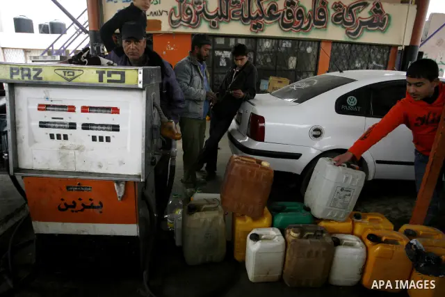 Palestinians wait to fill containers with fuel from a petrol station in Rafah in the southern Gaza Strip, on February 14, 2012, as the Palestinian authority calls on Egypt to provide more fuel. Photo by Abed Rahim Khatib