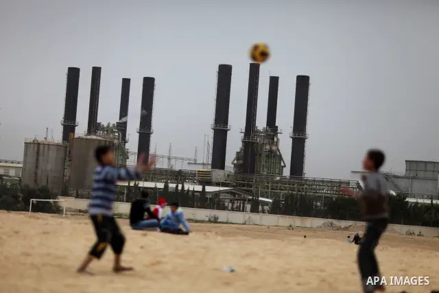 Palestinian boys play football in front of the power plant that generates electricity in Al-Nusirat in the central Gaza Strip, 14 February 2012. The Gaza Energy Authority said that the sole remaining power plant in the G...