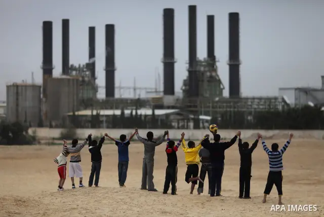 Palestinian boys play football in front of the power plant that generates electricity in Al-Nusirat in the central Gaza Strip, 14 February 2012. The Gaza Energy Authority said that the sole remaining power plant in the G...