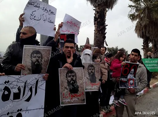 Palestinians hold up a pictures of Khader Adnan, a jailed senior member of Islamic Jihad who has been on hunger strike for nearly 60 days, during a protest outside Zief hospital in Safad, on February 15, 2012. Photo by S...