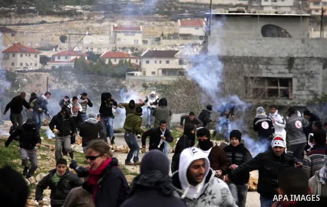 Palestinian youths hurl stones at Israeli troops during a protest in the village of Kufr Qaddum against the expansion of the nearby Jewish settlement of Kdumim, in the northern West Bank, Friday, Feb. 17, 2012. Photo by...