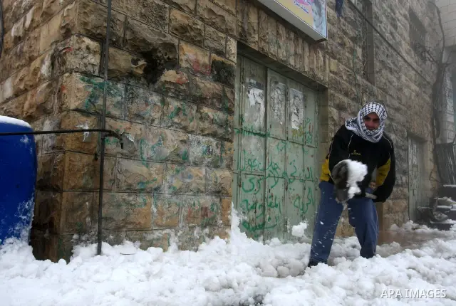 A Palestinian man shovels snow outside his house in the West Bank city of Hebron on February 18, 2012. Photo by Mamoun Wazwaz