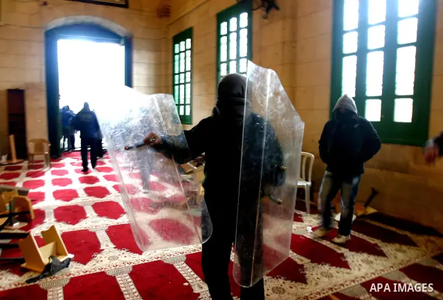 A masked Palestinian youth inside the al-Aqsa Mosque holds broken Israeli riot police shields after clashes on the Hareem el-Sharif (the Noble Sanctuary), or Temple Mount, in Jerusalem, 19 February 2012, as they battle P...