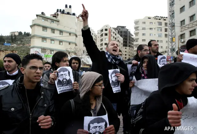 Palestinian women hold posters with the image of Khader Adnan, a senior member of Islamic Jihad jailed in Israel who has been on hunger strike for 64 days, during a protest calling for the release of Adnan and other Pale...