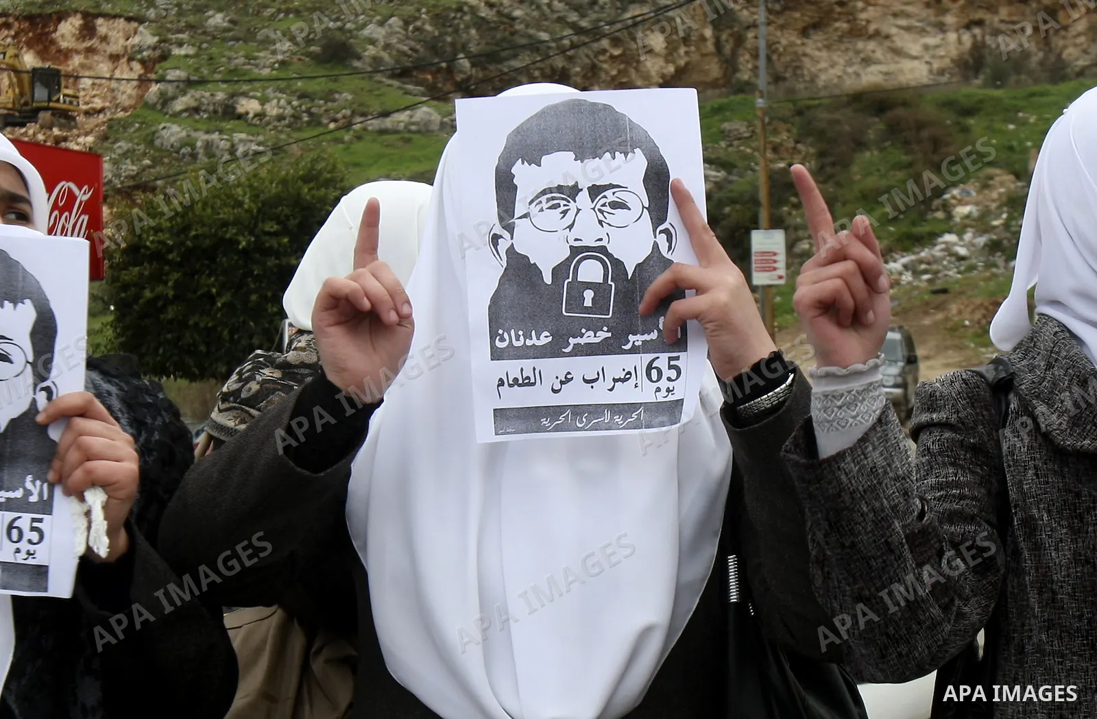 Palestinian women hold posters with the image of Khader Adnan, a senior member of Islamic Jihad jailed in Israel who has been on hunger strike for 64 days, during a protest calling for the release of Adnan and other Pale...
