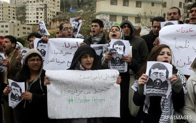 Palestinian women hold posters with the image of Khader Adnan, a senior member of Islamic Jihad jailed in Israel who has been on hunger strike for 64 days, during a protest calling for the release of Adnan and other Pale...