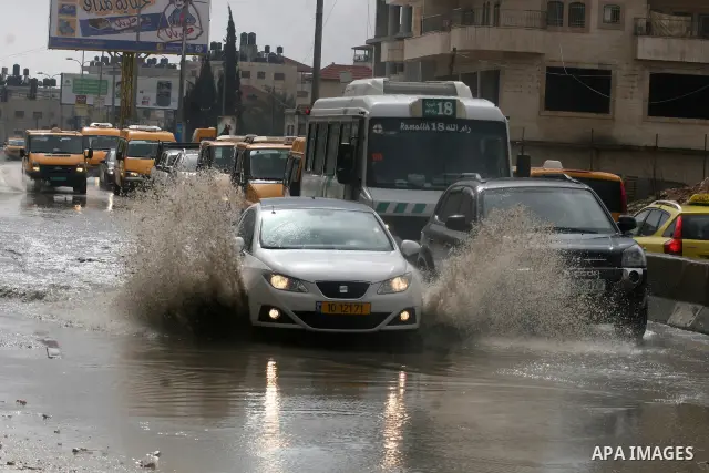 Palestinians walk in a street during the heavy rain of the winter, in west bank City of Ramallah, Feb. 19, 2012. Photo by Issam Rimawi