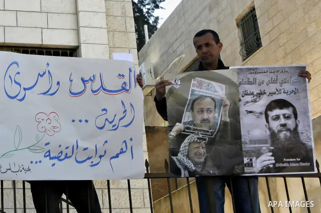 Palestinians hold posters with the image of Khader Adnan, a senior member of Islamic Jihad jailed in Israel who has been on hunger strike for 65 days, during a protest calling for the release of Adnan and other Palestini...