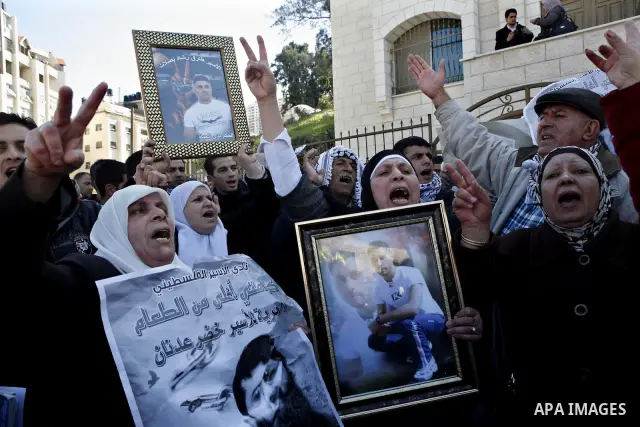 Palestinians hold posters with the image of Khader Adnan, a senior member of Islamic Jihad jailed in Israel who has been on hunger strike for 65 days, during a protest calling for the release of Adnan and other Palestini...