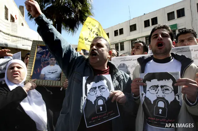 A Palestinian protestor holds a picture of Khader Adnan, 33, a senior member of Islamic Jihad jailed in Israel, during a demonstration in solidarity with Adnan, in the West Bank city of Nablus, on February 21, 2012, shor...