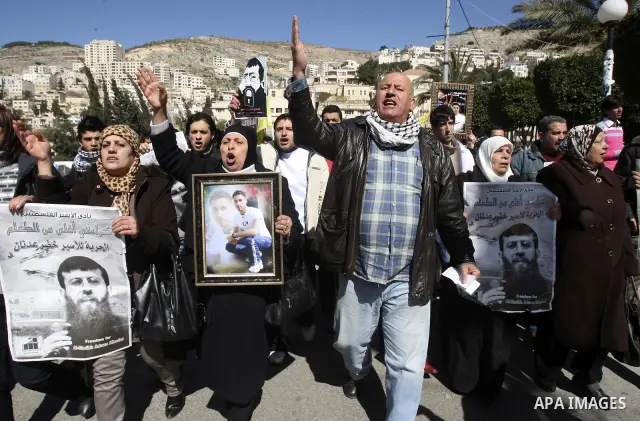A Palestinian protestor holds a picture of Khader Adnan, 33, a senior member of Islamic Jihad jailed in Israel, during a demonstration in solidarity with Adnan, in the West Bank city of Nablus, on February 21, 2012, shor...