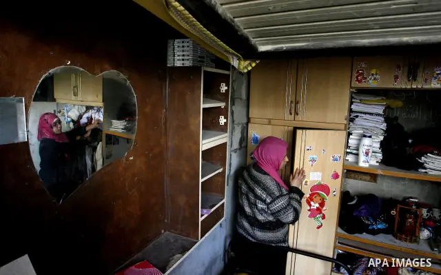 A Palestinian woman arranges her belongings inside her bad-built home in Khan Younis refugee camp in southern Gaza Strip, 21 February 2012. The United Nations Relief and Works Agency (UNRWA) stated that the Israeli block...
