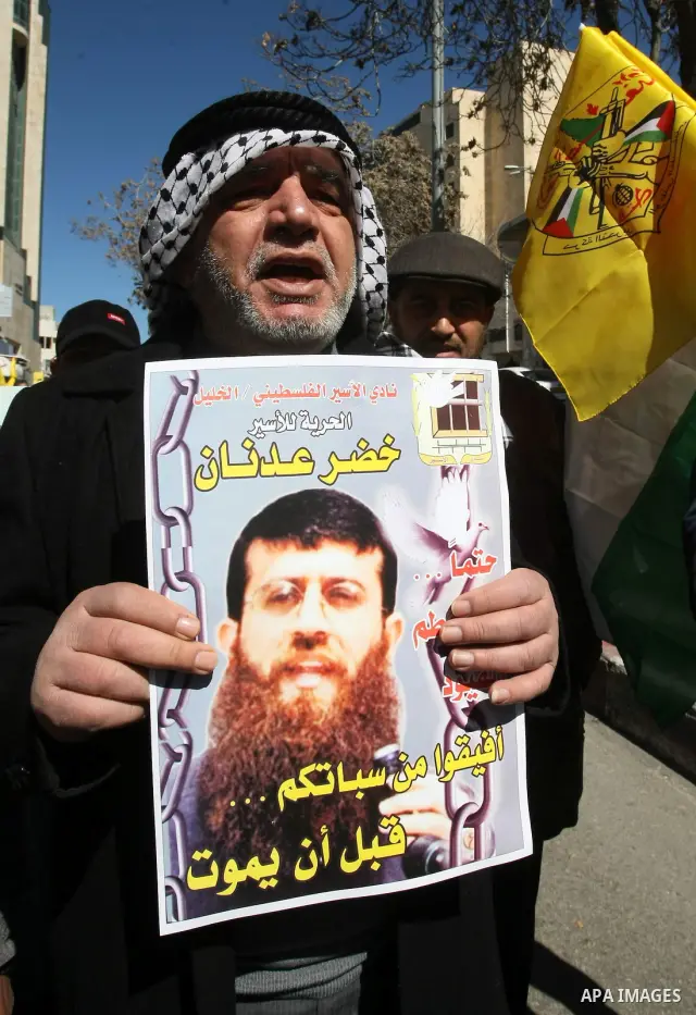 Palestinians holds a picture of Khader Adnan, a senior member of Islamic Jihad jailed in Israel, who has been on hunger strike for 66 days, during a protest calling for the release of Adnan and other Palestinians, in the...