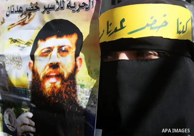 Palestinians holds a picture of Khader Adnan, a senior member of Islamic Jihad jailed in Israel, who has been on hunger strike for 66 days, during a protest calling for the release of Adnan and other Palestinians, in the...