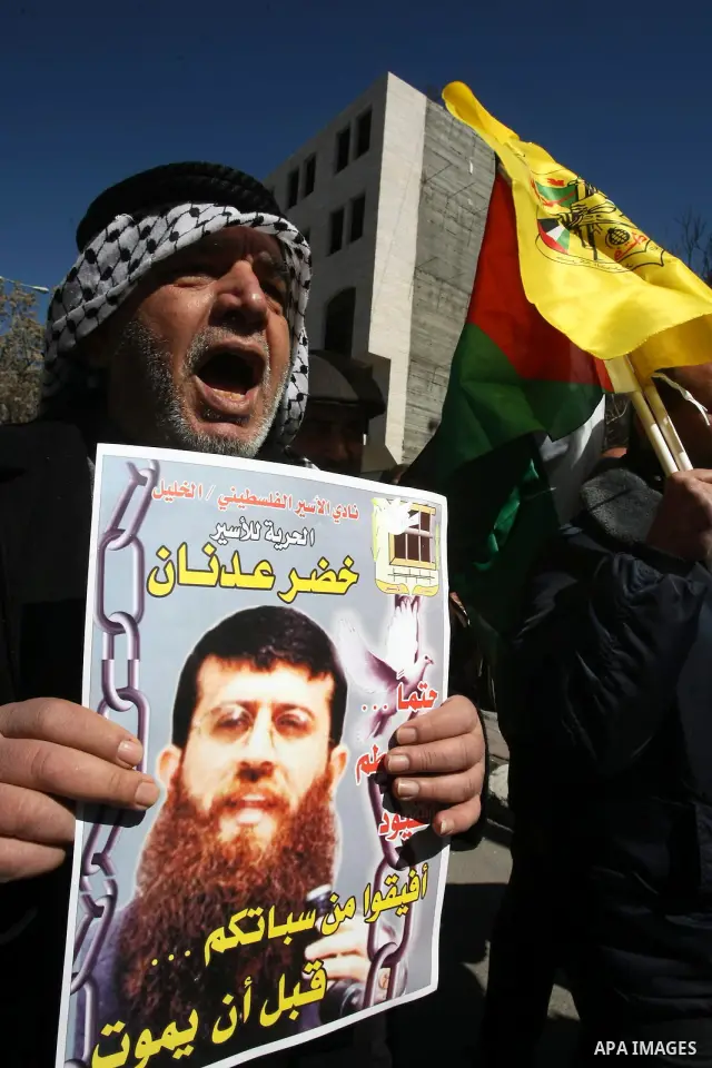 Palestinians holds a picture of Khader Adnan, a senior member of Islamic Jihad jailed in Israel, who has been on hunger strike for 66 days, during a protest calling for the release of Adnan and other Palestinians, in the...