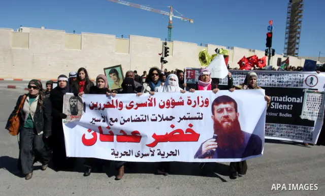 Palestinians hold a banner with an image of Islamic Jihad member Khader Adnan during a protest in his support in the West Bank city of Ramallah February 21, 2012. Adnan, held without trial by Israel, agreed on Tuesday to...