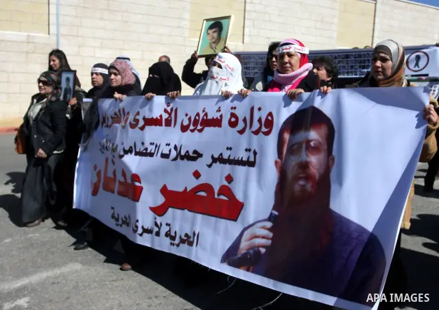 Palestinians hold a banner with an image of Islamic Jihad member Khader Adnan during a protest in his support in the West Bank city of Ramallah February 21, 2012. Adnan, held without trial by Israel, agreed on Tuesday to...