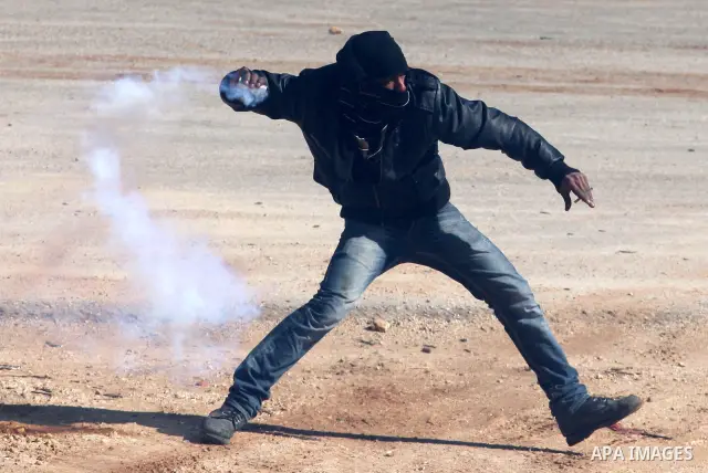 A Palestinian protester throws a stone towards Israeli troops during clashes outside Ofer prison near the West Bank city of Ramallah February 21, 2012. The clashes broke out after a protest in support of Islamic Jihad me...