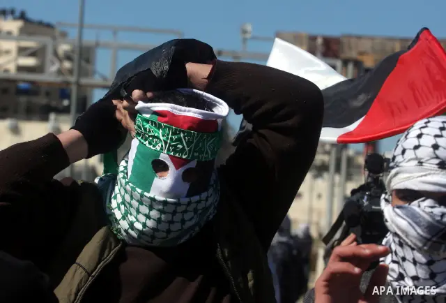A masked protestor throws a stone towards Israeli troops during clashes outside Ofer prison near the West Bank city of Ramallah February 21, 2012. The clashes broke out after a protest in support of Islamic Jihad member...