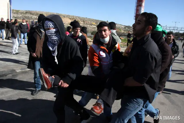Palestinian paramedics transfer a wounded on wheel to the hospital, during a demonstration outside the entrance of Ofer Prison near Ramallah in the occupied West Bank in support of a fellow prisoner who has ended on Febr...