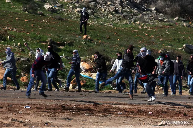 A Palestinian protester throws a stone towards Israeli troops during clashes outside Ofer prison near the West Bank city of Ramallah February 21, 2012. The clashes broke out after a protest in support of Islamic Jihad me...