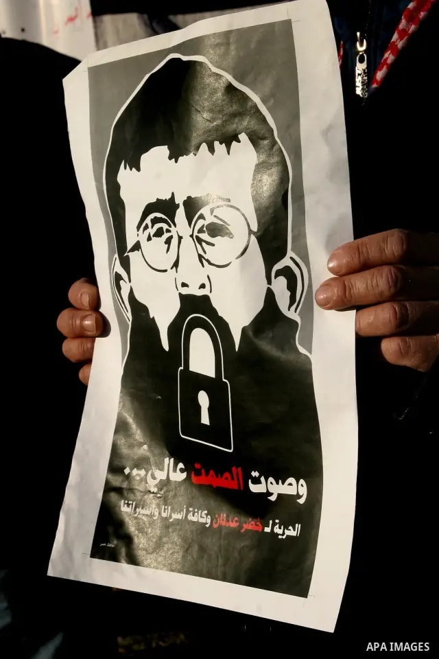 Palestinians holds a poster with a drawing depicting Islamic Jihad member Khader Adnan with a locked mouth, who has been on hunger strike for two months, during a demonstration in Jerusalem, Tuesday, Feb. 21, 2012. Adnan...