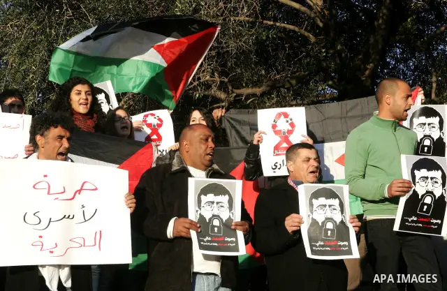 Palestinians holds a poster with a drawing depicting Islamic Jihad member Khader Adnan with a locked mouth, who has been on hunger strike for two months, during a demonstration in Jerusalem, Tuesday, Feb. 21, 2012. Adnan...