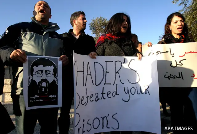 Palestinians holds a poster with a drawing depicting Islamic Jihad member Khader Adnan with a locked mouth, who has been on hunger strike for two months, during a demonstration in Jerusalem, Tuesday, Feb. 21, 2012. Adnan...